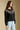 Side angle view of a woman wearing the Saltwater Luxe Joss Sweater on a neutral background with hands at sides