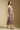Side angle view of a woman wearing the Saltwater Luxe Juli Midi Dress on a neutral background with boots and arms at sides