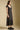 Side angle view of a woman wearing the Saltwater Luxe Junniper Midi Dress on a neutral background with shoes