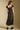 Back view of a woman wearing the Saltwater Luxe Junniper Midi Dress on a neutral background