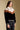 Side angle view of a woman wearing the Saltwater Luxe Kaira Jacket on a neutral background with black jeans