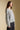 Side angle view of a woman wearing the Saltwater Luxe Kirra Sweater on a neutral background with hands at sides
