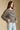 Side angle view of a woman wearing the Saltwater Luxe Kirra Sweater on a neutral background with hands on hips