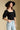Front view of a woman wearing the Saltwater Luxe Lewis Top on a neutral background with bluejeans and hat