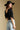 Back view of a woman wearing the Saltwater Luxe Lewis Top on a neutral background with jeans