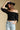 Front view of a woman wearing the Saltwater Luxe Lewis Top on a neutral background with black flat brimmed hat