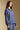 Side view of a woman wearing the Saltwater Luxe Liu Indigo Top on a neutral background with arms lowered at sides
