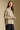 Side angle view of a woman wearing the Saltwater Luxe Liu Top on a neutral background with hands clasped