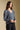 Side angle view of a woman wearing the Saltwater Luxe Lyrra Top on a neutral background with hands clasped 
