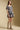 Side angle view of a woman wearing the Saltwater Luxe Malinda Mini Dress on a neutral background with boots