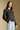 Side angle view of a woman wearing the Saltwater Luxe Margow Sweater on a neutral background with hand on hip