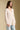 Side angle view of a woman wearing the Saltwater Luxe Maxine Simple Sweater on a neutral background with hands at sides