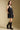 Side angle view of a woman wearing the Saltwater Luxe Miniya Mini Dress on a neutral background with hand in pocket