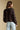 Back view of a woman wearing the Saltwater Luxe Nera Top on a neutral background with jeans