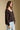 Side angle view of a woman wearing the Saltwater Luxe Nera Top on a neutral background with bluejeans
