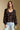 Front view of a woman wearing the Saltwater Luxe Nera Top on a neutral background with bluejeans and arms at sides