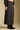 Side angle view of a woman wearing the Saltwater Luxe Nolla Midi Skirt on a neutral background with top and boots