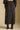 Back view of a woman wearing the Saltwater Luxe Nolla Midi Skirt on a neutral background with matching top and boots