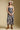 Front view of a woman wearing the Saltwater Luxe Novi Midi Dress and boots on a neutral background