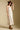 Side angle view of a woman wearing the Saltwater Luxe Peni Midi Dress on a neutral background with hat
