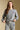 Frontview of a woman wearing the Saltwater Luxe Perry Heather Grey Pullover on a neutral background with arms on hem of shirt