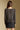 Back view of a woman wearing the Saltwater Luxe on a neutral background with black skirt and arms at sides