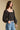 Side angle view of a woman wearing the Saltwater Luxe on a neutral background with bluejeans and hand in pocket