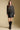 A full body front view of a woman wearing the Saltwater Luxe on a neutral background with faux leather skirt
