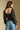Back view of a woman wearing the Saltwater Luxe on a neutral background with bluejeans and arms at sides