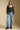 A full body front view of a woman wearing the Saltwater Luxe on a neutral background with bluejeans
