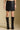 Front view of a woman wearing the Saltwater Luxe Ralie Skirt with knee high boots and hands at sides