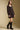 Side angle view of a woman wearing the Saltwater Luxe Ralph Mini Dress on a neutral background with boots