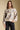 Front of a woman wearing the Saltwater Luxe Ronnie Sweater on a neutral background with black pants with one hand in pocket