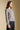 Side angle view of a woman wearing the Saltwater Luxe Saskia Sweater on a neutral background with black jeans