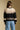 Back view of a woman wearing the Saltwater Luxe Scarlit Sweater on a neutral background with jeans