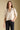 Front view of a woman wearing the Saltwater Luxe Stacia Top on a neutral background with hand in pants pockets