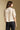 Back view of a woman wearing the Saltwater Luxe Stacia Top on a neutral background with pants