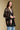 Side angle view of a woman wearing the Saltwater Luxe Stari Sweater on a neutral background with hands clasped