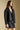Side angle view of a woman wearing the Saltwater Luxe Sylvie Jacket and matching skirt on a neutral background