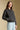Side angle view of a woman wearing the Saltwater Luxe Tamira Jacket on a neutral background with hand in pocket