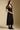 Side angle view of a woman wearing the Saltwater Luxe Tamra Midi Dress on a neutral background with hands clasped