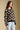Side angle view of a woman wearing the floral Saltwater Luxe Vincent Sweater on a neutral background with hand in pocket
