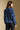 Back view of a woman wearing the Saltwater Luxe Xenia Sweater on a neutral background with hands at sides
