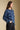 Side angle view of a woman wearing the Saltwater Luxe Xenia Sweater on a neutral background with hands in pockets