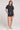 A full body front view of a woman wearing the Saltwater Luxe Short Sleeve Black Pullover on a neutral background