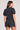 Back view of a woman wearing the Saltwater Luxe Short Sleeve Black Pullover on a neutral background