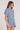 Side angle view of a woman wearing the Saltwater Luxe Short Sleeve Worn Blue Pullover on a neutral background