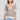 A front view of a woman wearing the Saltwater Luxe Siera Natural Top on a neutral background with her hands at her sides
