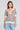 A front view of a woman wearing the Saltwater Luxe Siera Natural Top on a neutral background with her hands at her sides