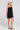 Side angle view of a woman wearing the Saltwater Luxe Valey Black Mini Dress on a neutral background
